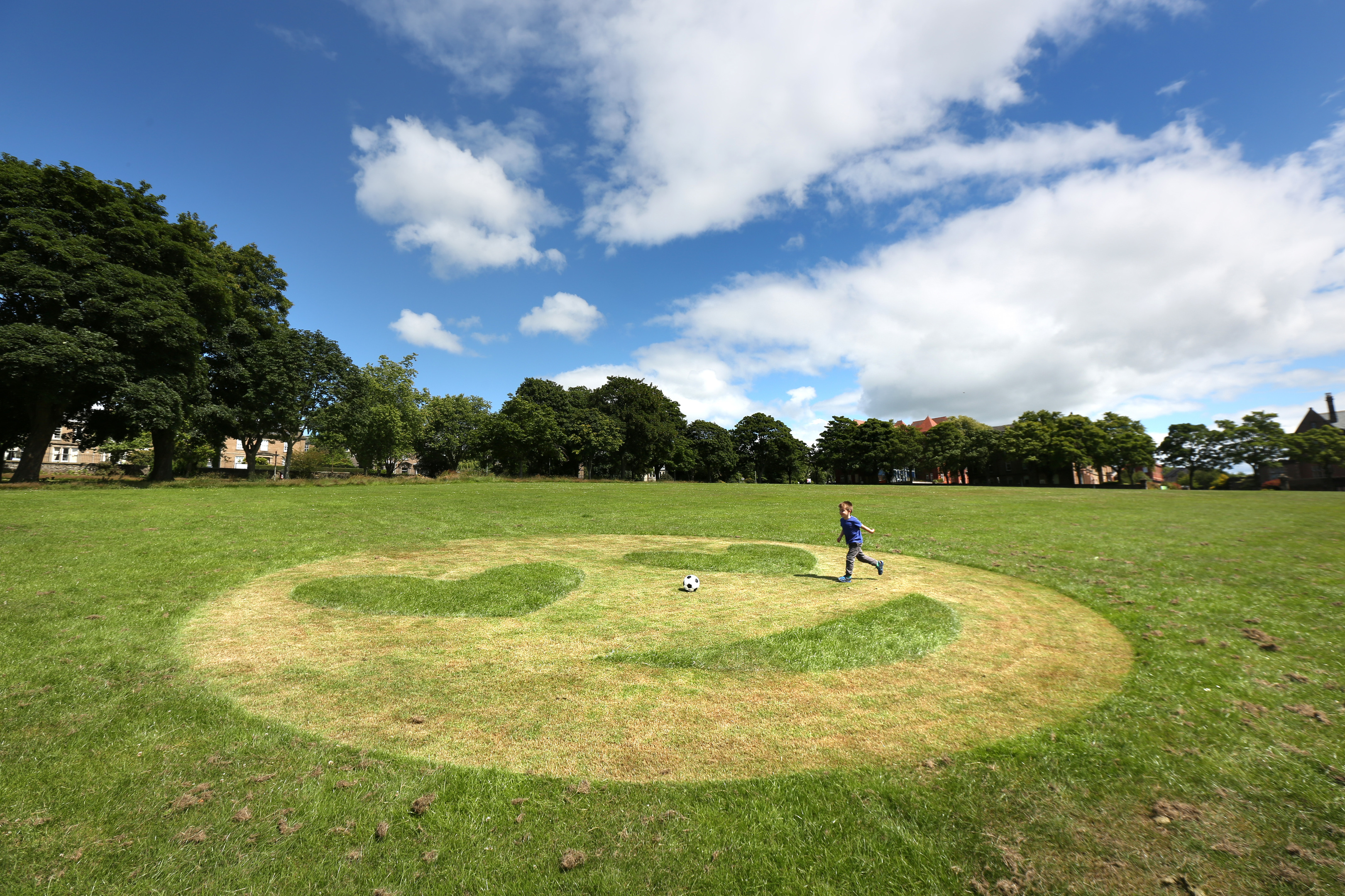 Murray Allan (4) playing football beside the emoji in Dudhope Park.