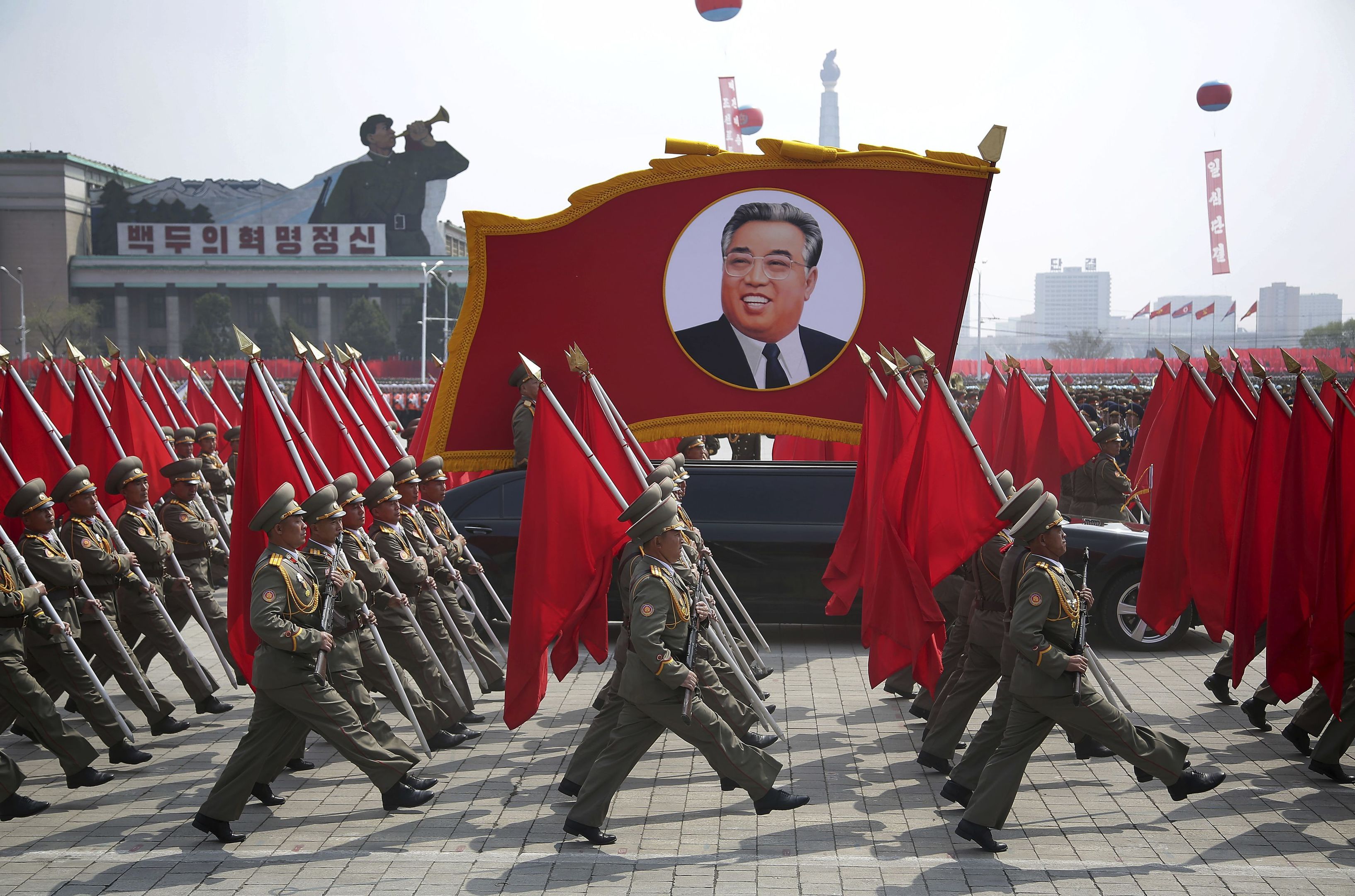North Korean soldiers carry flags and a photo of late leader Kim Il Sung as they march across Kim Il Sung Square during a military parade.