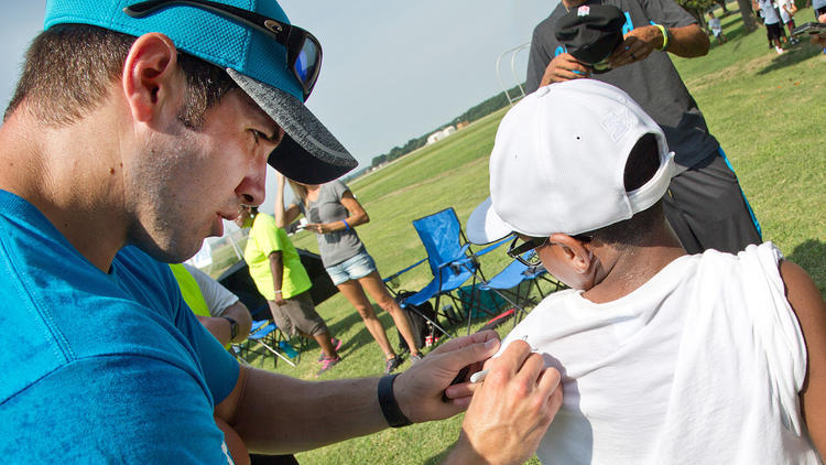 The NFL star signs an autograph at the camp.