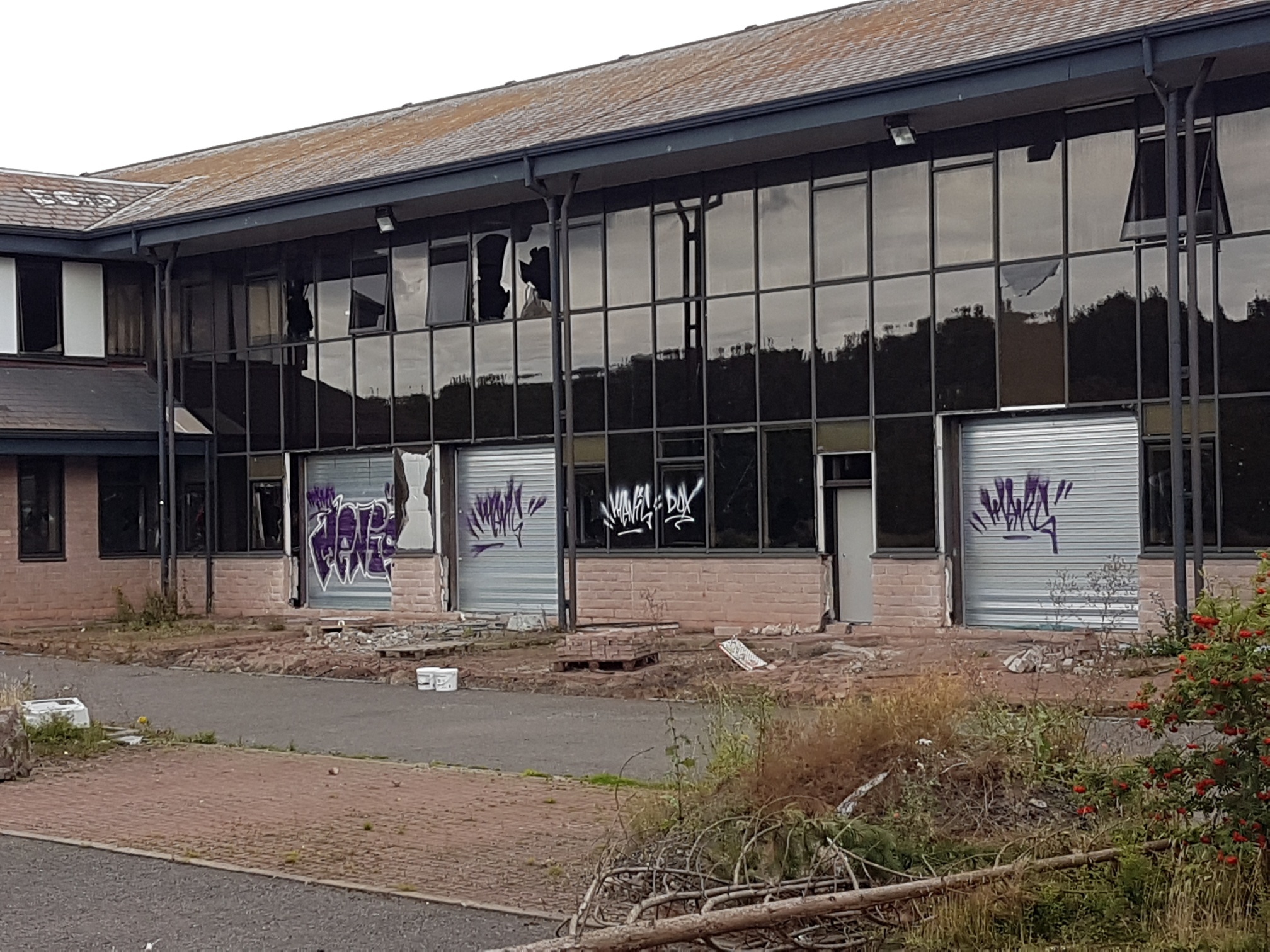 The building's windows have been smashed and its shutters are covered in graffiti.