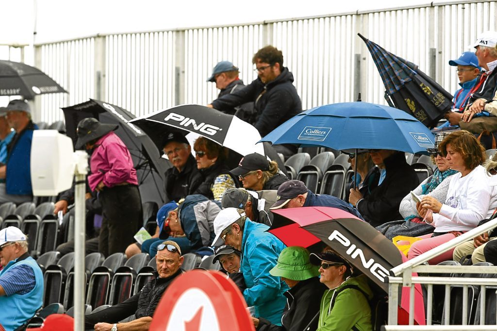 Golf fans take shelter from the rain again during the Women's British Open in high summer in Scotland.