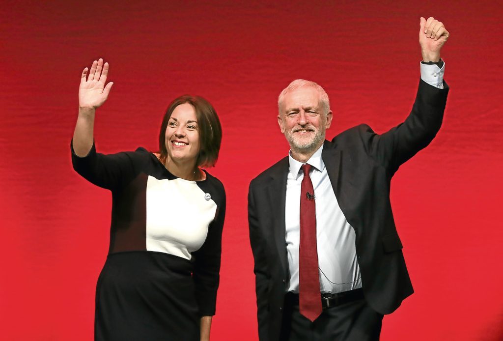 Photo shows Former Scottish Labour leader Kezia Dugdale and former Labour leader Jeremy Corbyn in front of a red background.