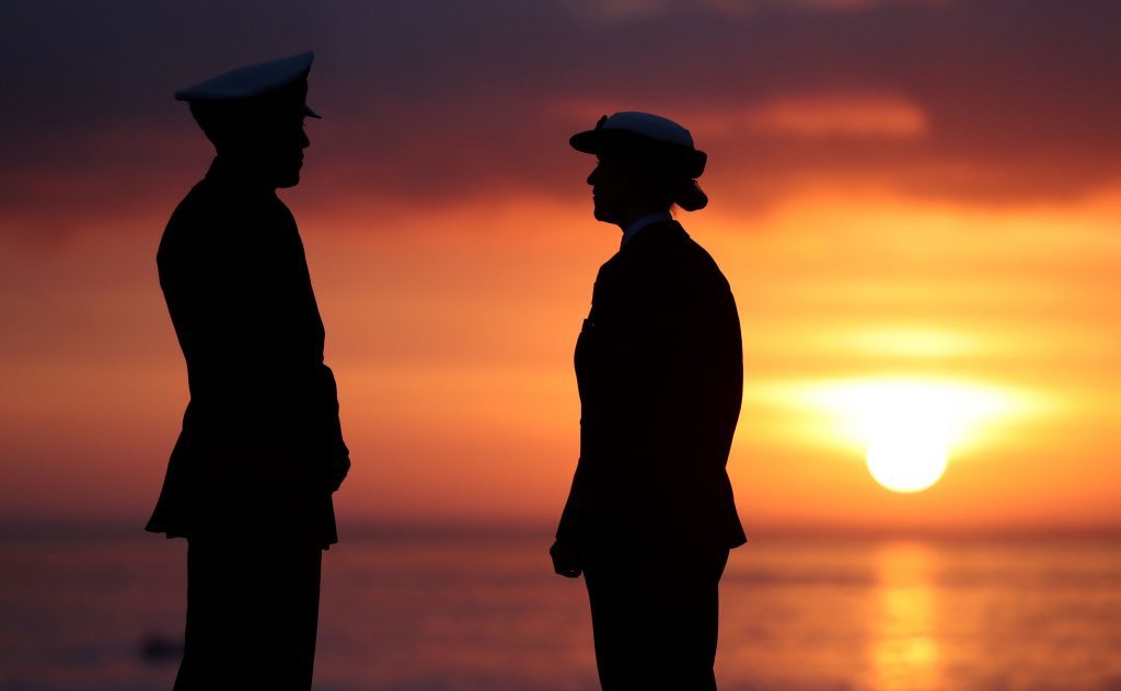 Two crew members chat as the sun rises next to the HMS Queen Elizabeth