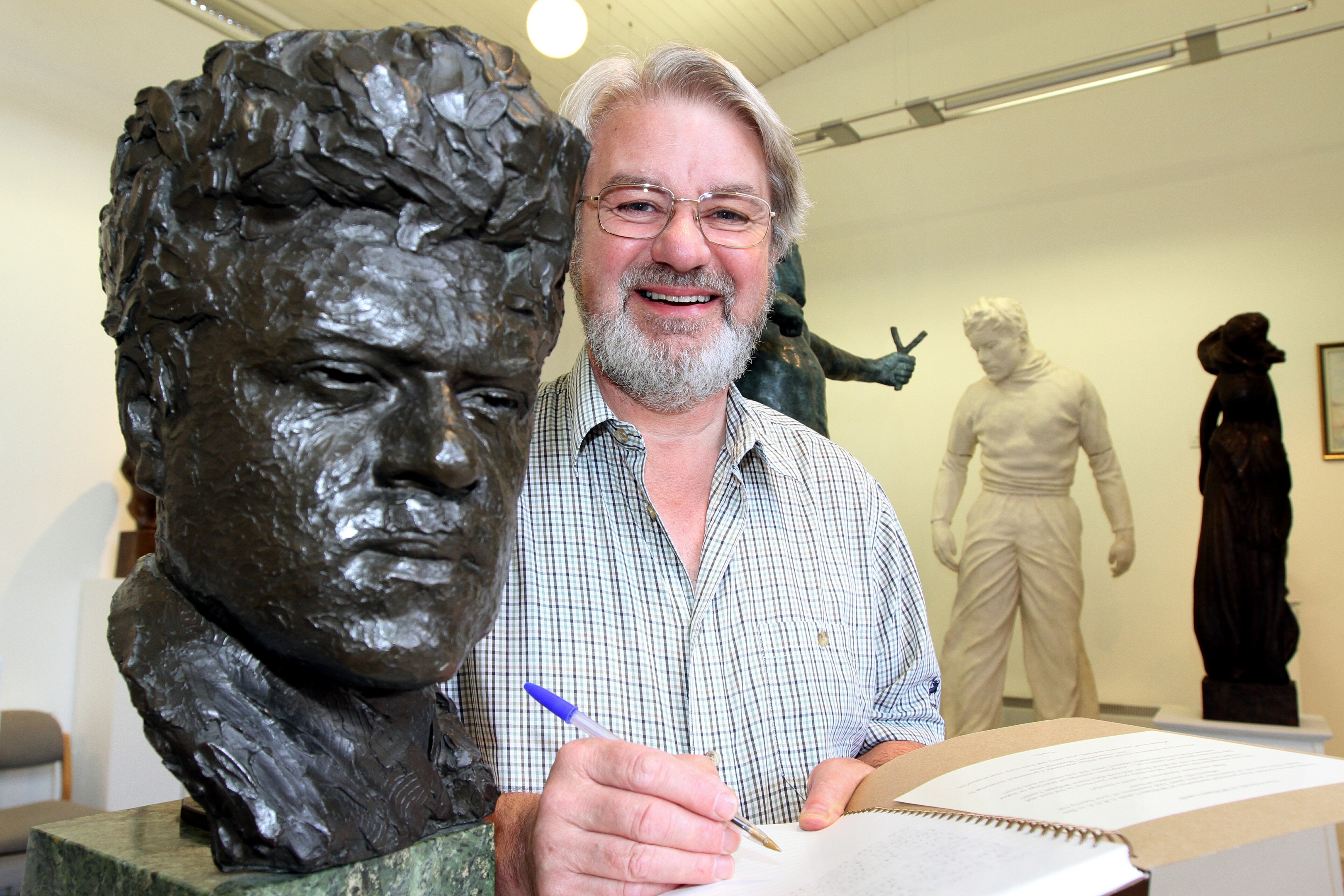 Friends chairman Norman Atkinson signs the memory book alongside a self-sculpture of the man himself.