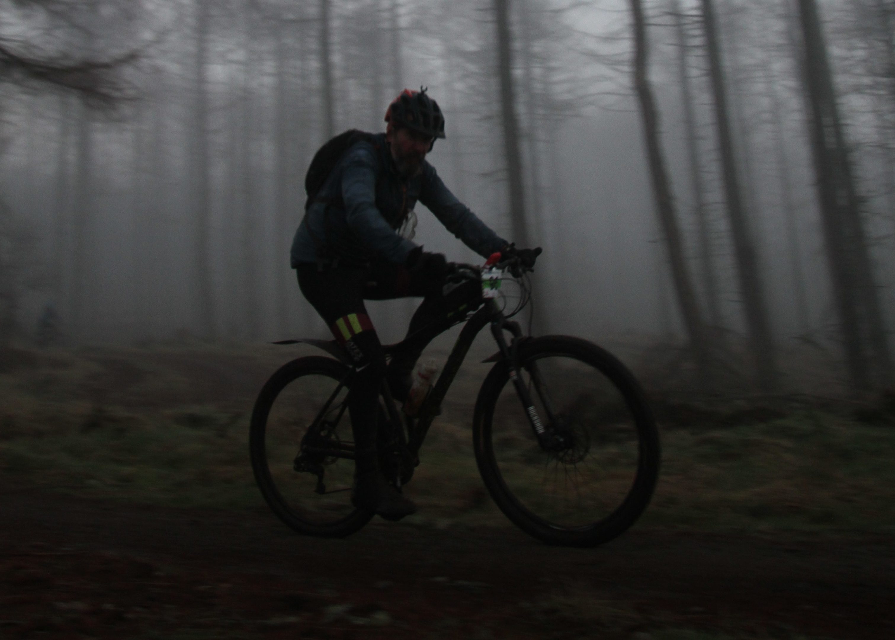 Night starts to fall at the Strathpuffer. Scot riding through the lower forest .