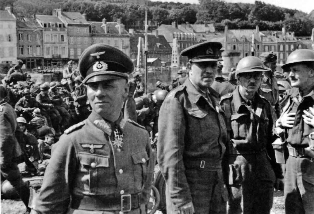 B&W photo of Rommel and other German officers with members of the 51st highland division behind them at St Valery in 1940