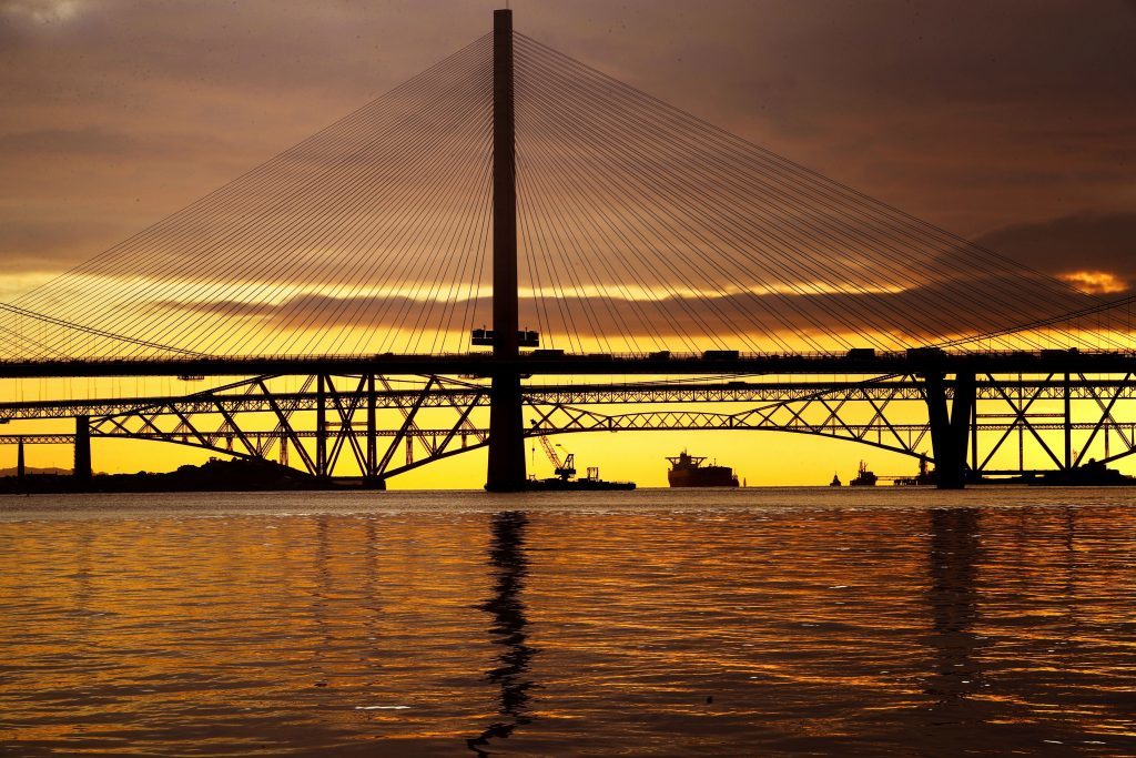 A view of the new Queensferry Crossing, alongside the Forth Road Bridge and the Forth Bridge, at sunrise on the first day of operational use.