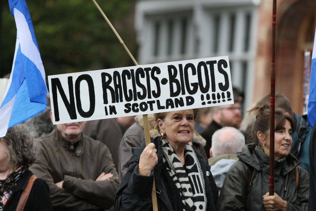Woman holding banner which reads 'No racists, bigots in Scotland'