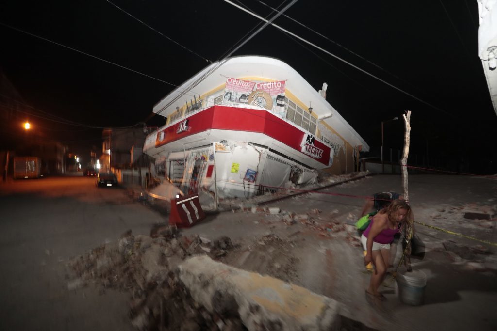 A woman walks past a collapsed building after a 7.1 earthquake, in Jojutla, Morelos state, Mexico