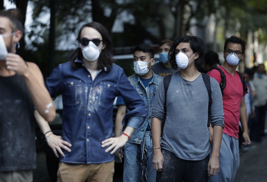 Volunteers wearing dust masks wait in line to pass out rubble as rescue workers search inside a collapsed building
