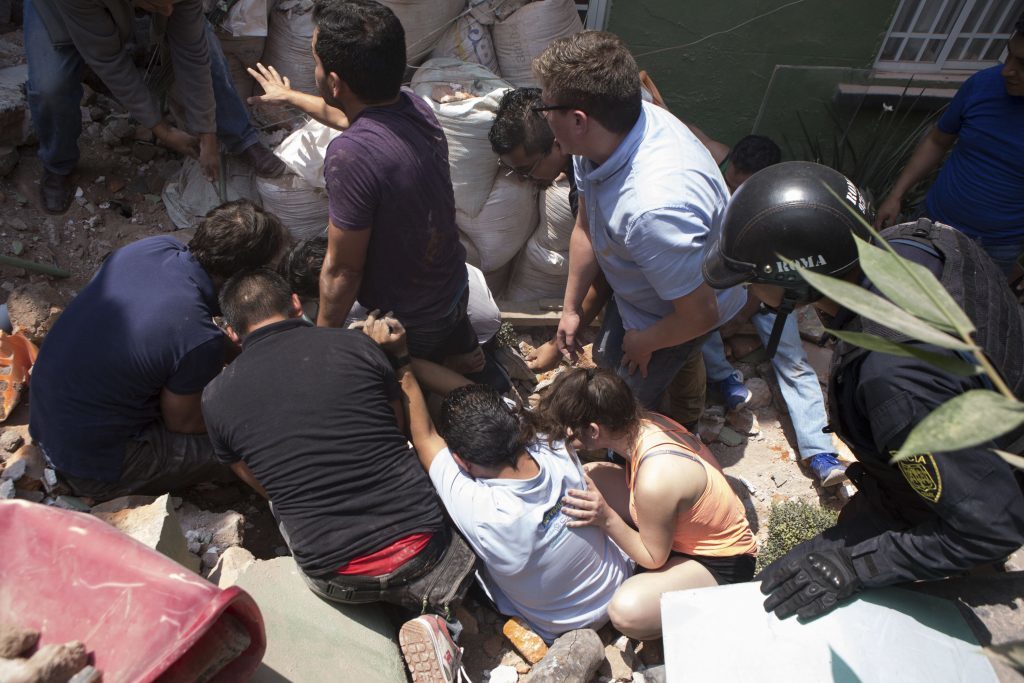 People prepare to pull out a man alive from a collapsed building in the Condesa neighborhood