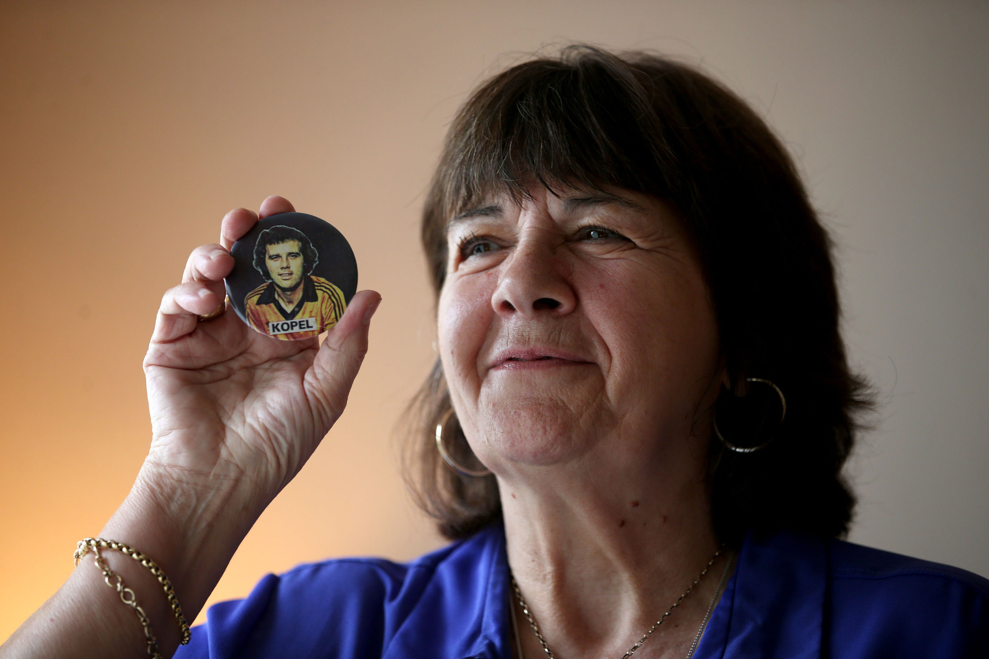 Amanda Kopel holds a football badge of her late husband Frank.