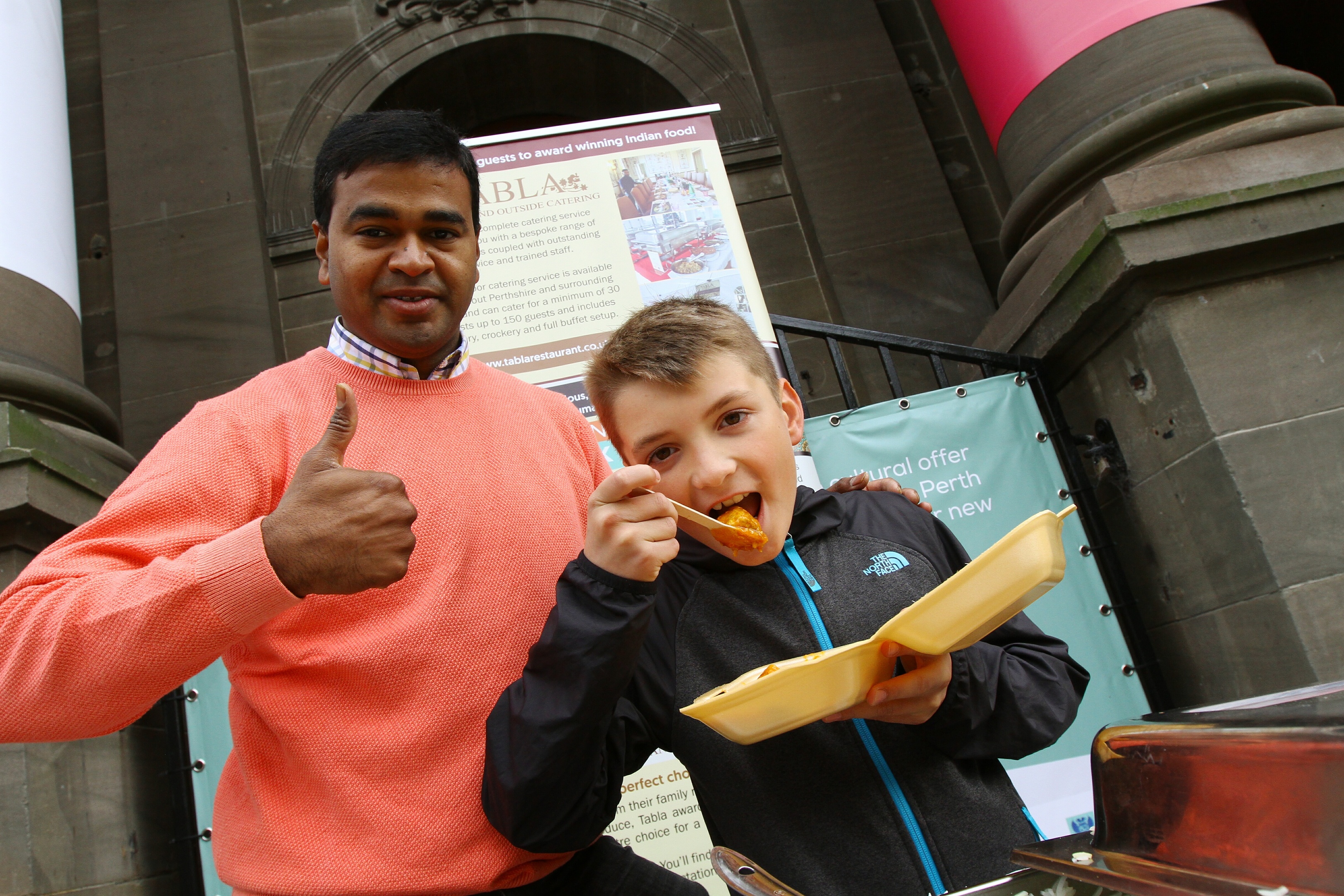 Praveen Kumar with Josh Ferris tucking into his curry, as part of World Food Day in Perth.