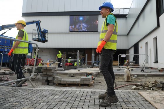 Perth Theatre exterior with new added screen. Workers making the final touches to the exterior of the Perth Theatre. A giant screen is showing timelapse video of the work taking place.