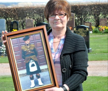 Catherine Kinnear holds a picture of her son at Falkland Cemetery where he is buried.