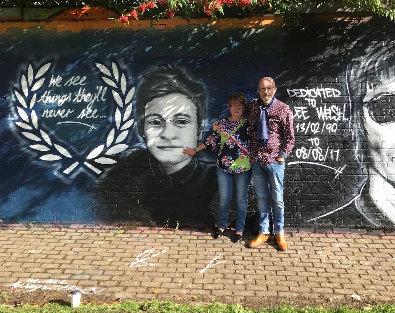 Lee's parents Phil and Lesley with a mural dedicated to their son.