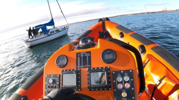 The crew pull alongside with the sailing vessel transmitting the distress signal.