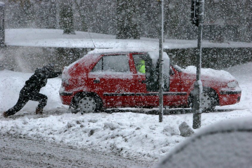 A man pushes a car through snow in Dundee, 2010.