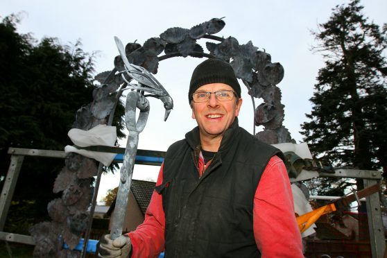 Metalwork sculptor Adam Booth with his arch and one of the "three craws",