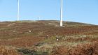 Beaters lined out below turbines on moorland in Scotland. Land uses, side by side like this, are increasingly commonplace today in Scotland.
