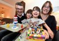 Nick and Susan Woollacott with their daughters Heather (left) and her sister Izzy with a rocket and noodle restaurant made out of Lego.