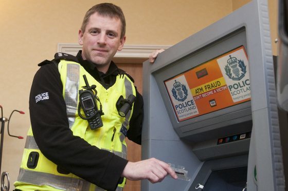 Community police officer, Scott Anderson, demonstrates ATM scams at the pop-up event