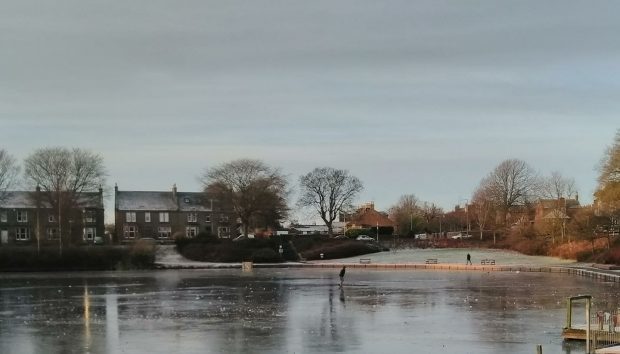 A boy plays football on the frozen pond.