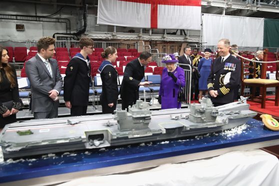Queen Elizabeth II  looks at a cake made by David Duncan during the Commissioning Ceremony of HMS Queen Elizabeth at HM Naval Base