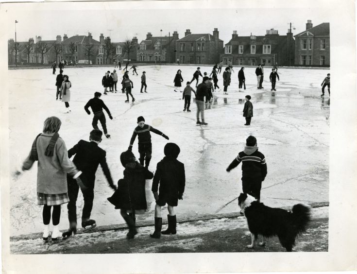 Photograph showing large numbers of people, young and old, having fun with a day of ice skating at Stobsmuir Pond,  December 28, 1962.