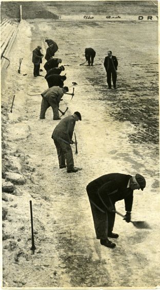 Manager Jerry Kerr watches on as groundsman take picks and shovels to the frozen pitch at Tannadice Park, Dundee. January 1963.