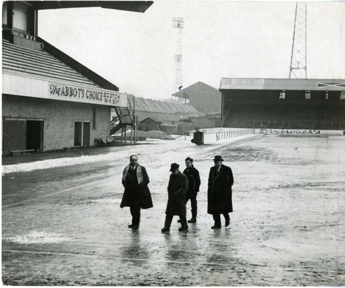 Photograph showing Jerry Kerr (manager), Ernie Robertson (chairman), Albert Lorimer (groundsman), Johnstone Grant (director) walking along an ice covered Tannadice Park. January 1963.