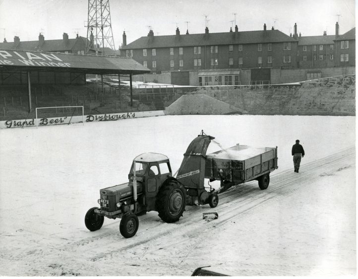 Photograph showing the groundskeepers as they use a snow blower to clear the snow from the grounds at Tannadice Park. 20 February 1963.