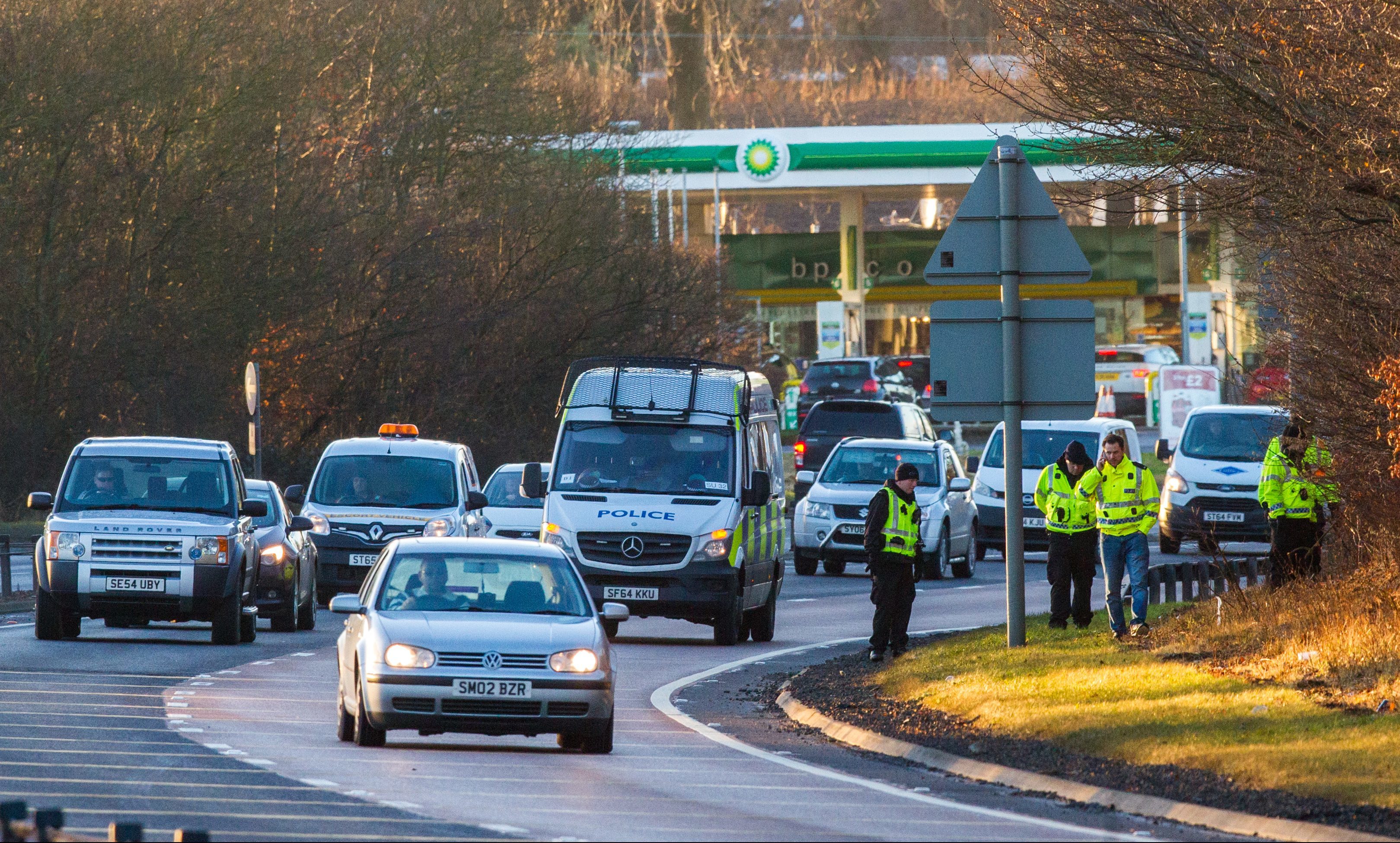 Police walking eastbound along the side of the A90 with a slow crawling police van accompanying them.