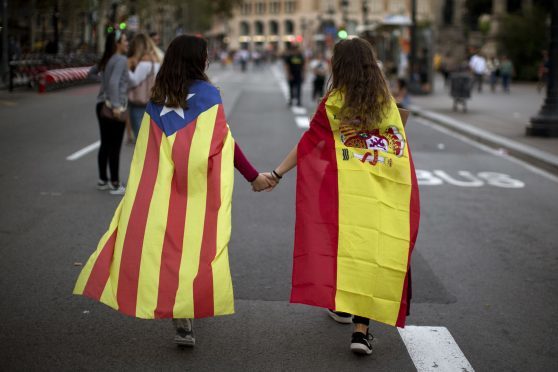 Irene Guszman, 15, wearing a Spanish flag and Mariona Esteve, 14, wearing an estelada or independence flag, walk along the street to take part at a demonstration in Barcelona, Spain.