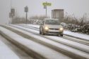A car makes its way through the snow in Main Road, Gateside.