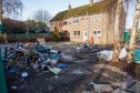 Old fridges, skips, and general waste in a garden causing an eyesore