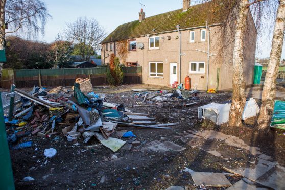 Old fridges, skips, and general waste in a garden causing an eyesore