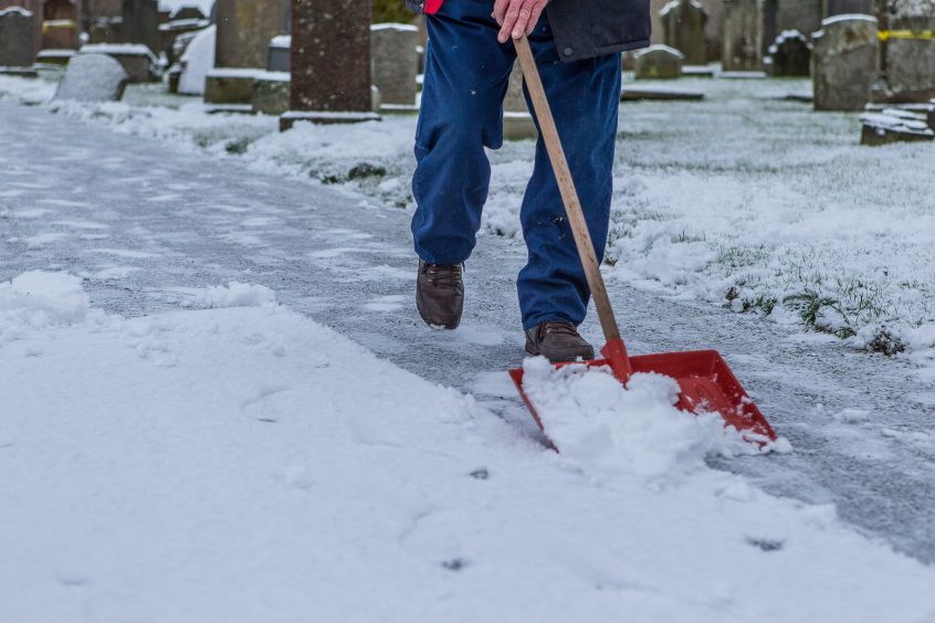 A man clears snow from the driveway of Meigle Church