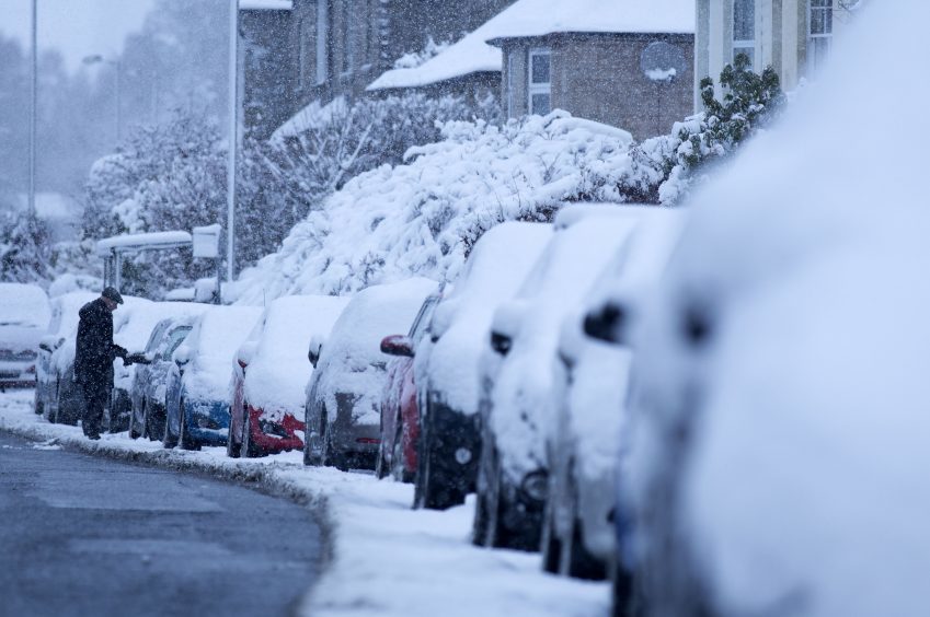 Heavy snow covers parked cars in Midlothian near Edinburgh.