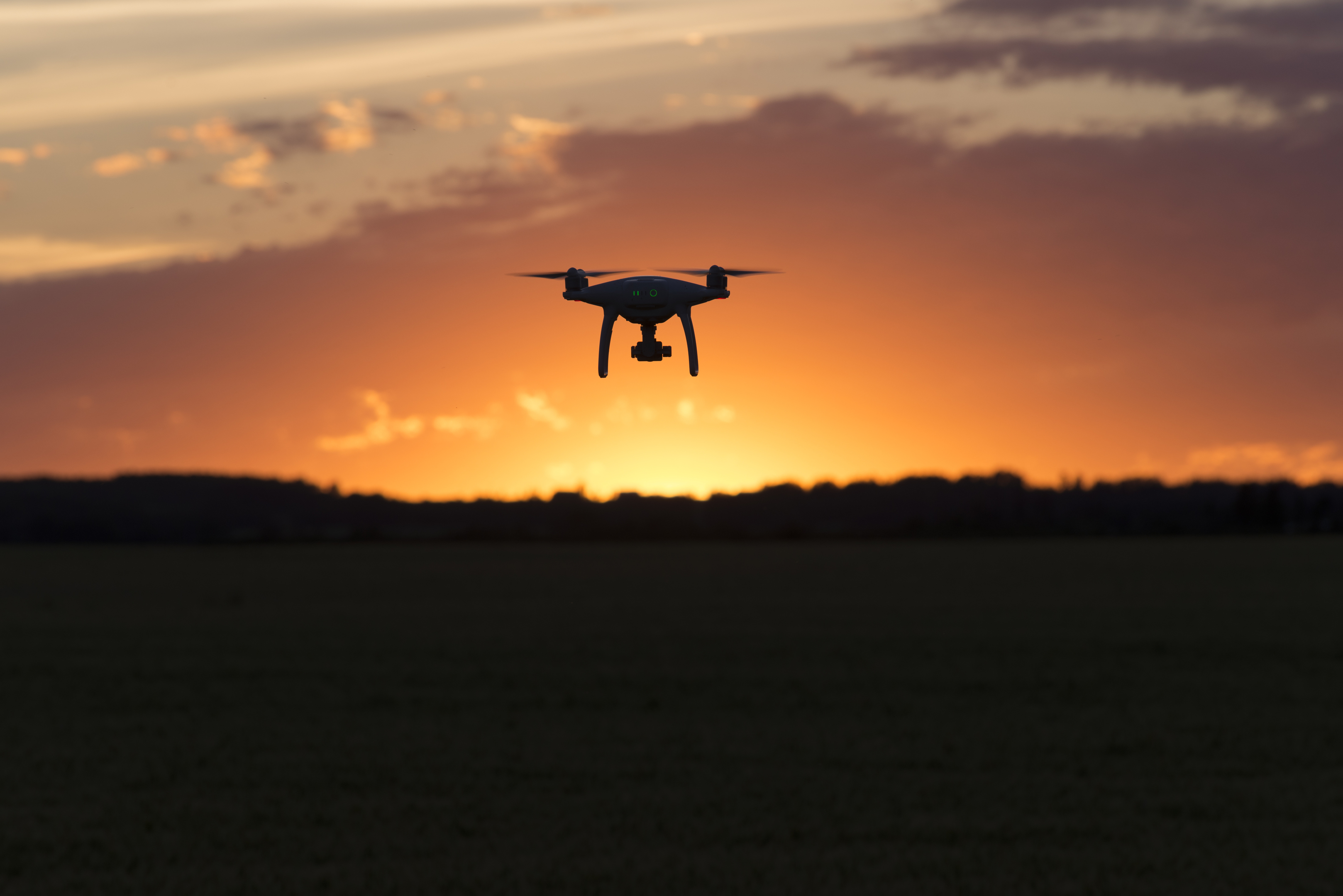 Drone silhouetted against orange sunset