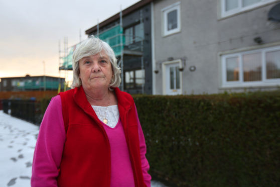 Margaret Davidson outside her property on Dryburgh Street. The house to the left of hers is currently undergoing work to install the external wall insulation, which she is not eligible for according to the council.