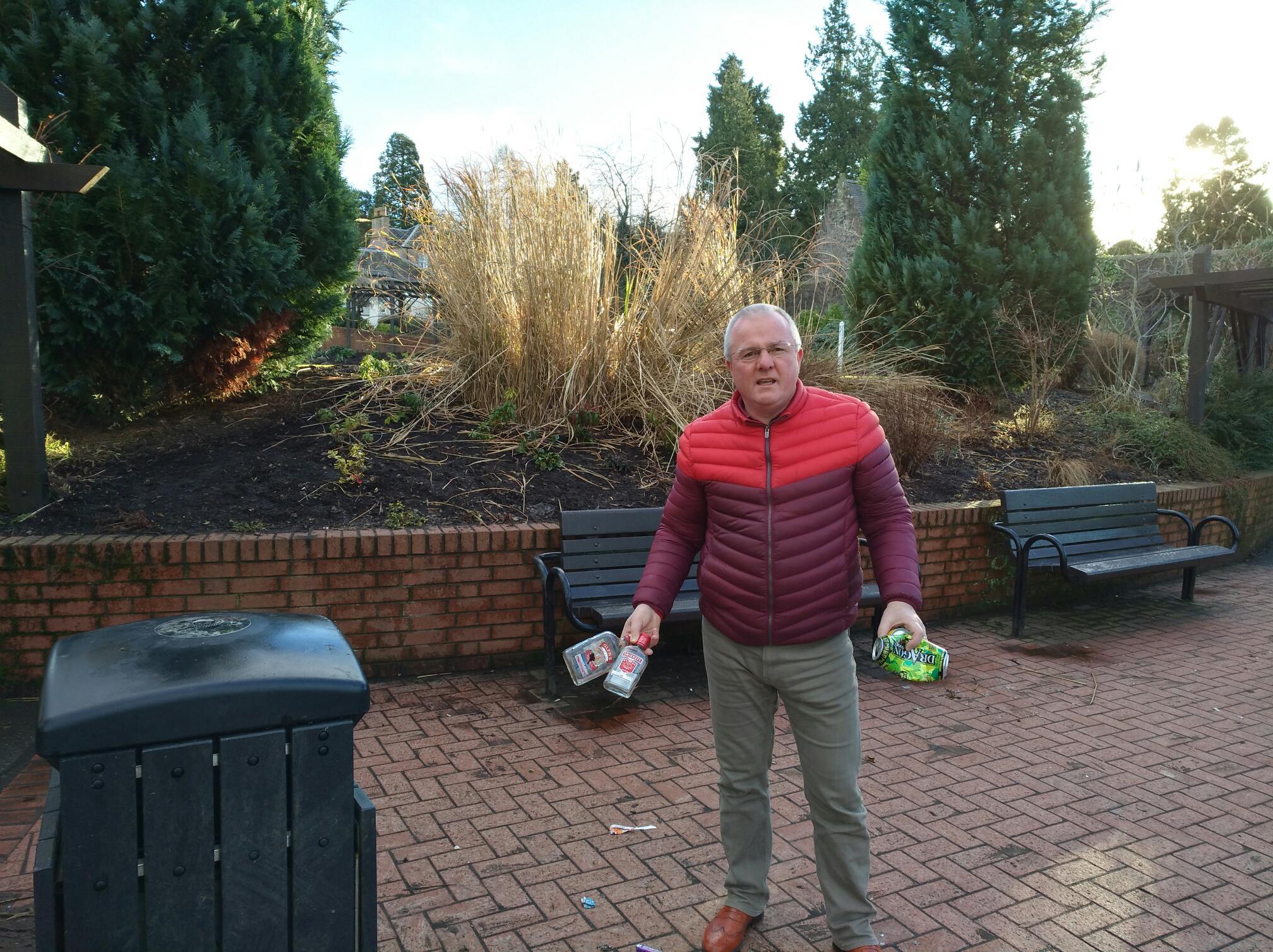 Councillor Peter Barret helps clear up some of alcohol bottles left discarded after another night of underage drinking.