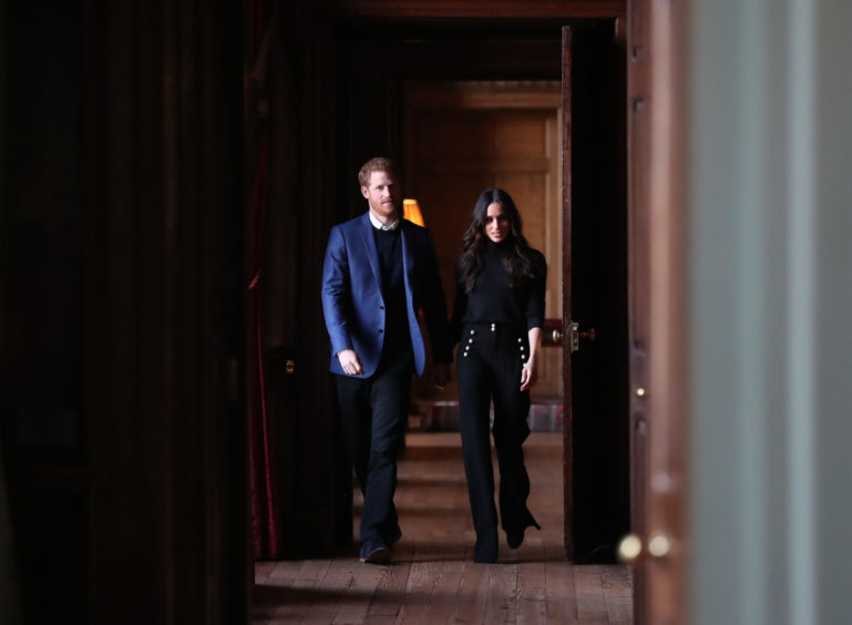 Prince Harry and Meghan Markle walk through the corridors of the Palace of Holyroodhouse on their way to a reception for young people