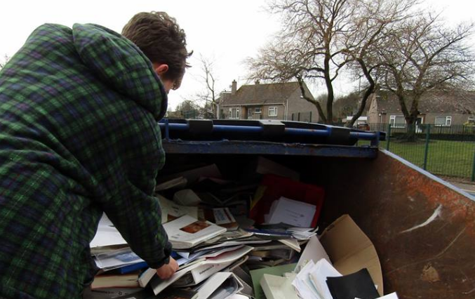 A volunteer sifts through a skip filled with recyclable materials at the old school campus