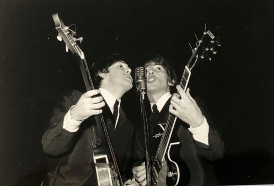 Paul McCartney and George Harrison on stage at the Caird Hall in 1964.