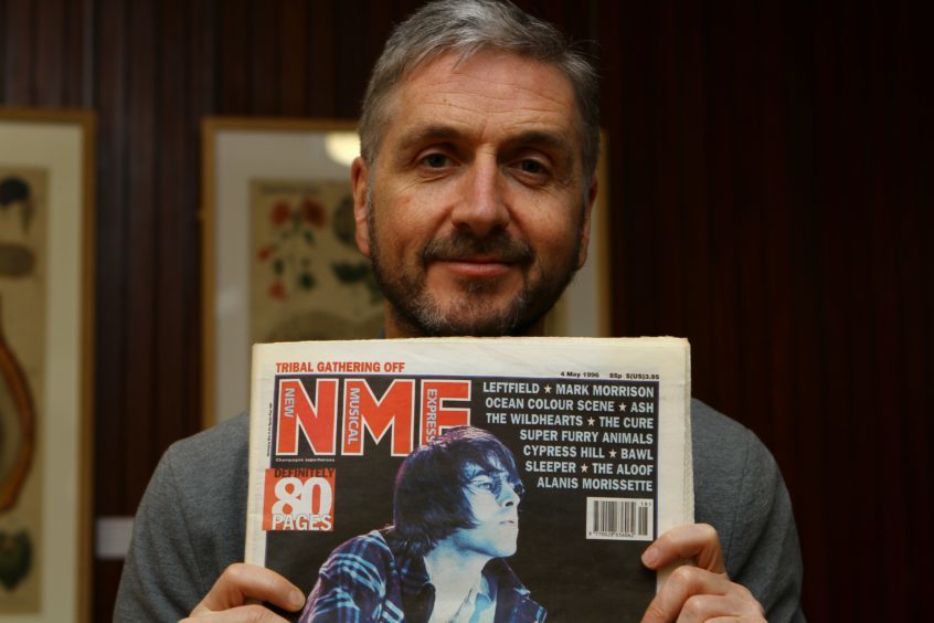 Former Dundee rock writer Roddy Isles holds a copy of NME with Oasis on the front