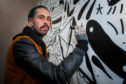 Richard Davies working on wall murals at his recently opened coffee shop, Daily Grind