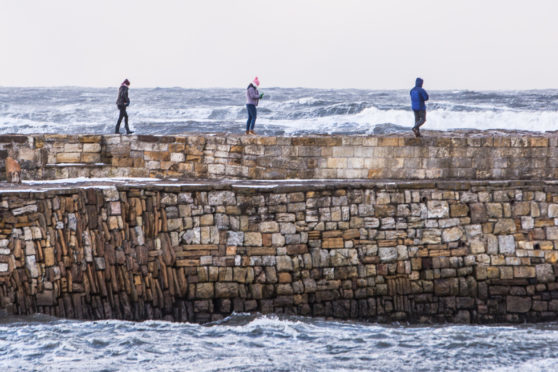 St Andrews has a dramatic backdrop of turbulent sea as these students find out, some taking unecessary risks by climbing the top wall.