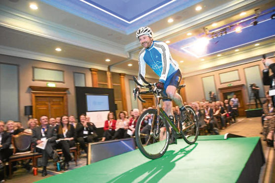 Dundee entrepreneur Chris van der Kuyl takes to the stage at the Entrepreneurial Scotland conference on Mark Beaumont's bike.