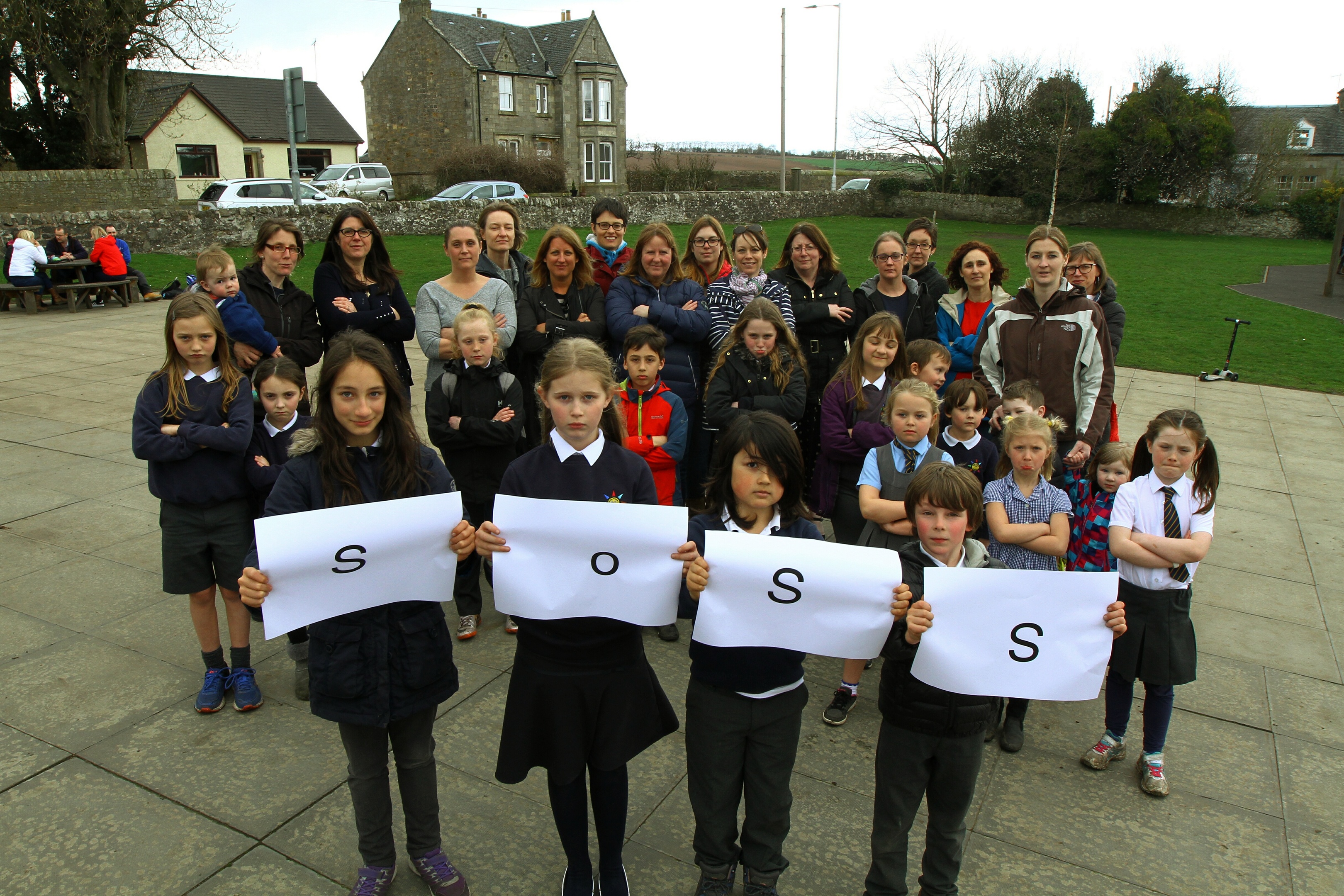 Ceres Primary pupils Marnie Raval, Maddie Burns, Kazuo O'Connor and Moritz Gerken - Dempster holding up SOSS (Save Our School Secretaries) with some of the pupils and parents at Ceres Primary School